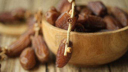 Bowl with dried dates on wooden table