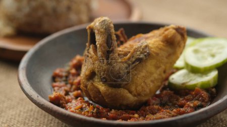 Téléchargez les photos : Poulet frit dans une assiette d'argile avec sambal. Alimentation indonésienne. - en image libre de droit