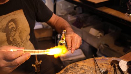Photo for The glass craftsman is burning a piece of glass with torch flame. Sydney, 28 September 2023. - Royalty Free Image
