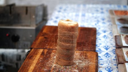 Téléchargez les photos : Krtskalcs est fabriqué à partir de pâte à levure sucrée, dont une bande est filée, puis enroulée autour d'une broche de cuisson tronquée en forme de cône, et roulée dans du sucre granulé. Il est torréfié au charbon de bois. - en image libre de droit