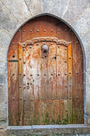Ainsa, Very old wooden entrance door under an ogival vaulted wall
