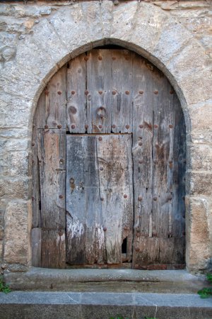 Ainsa, puerta de entrada de madera muy antigua bajo una pared abovedada ojival