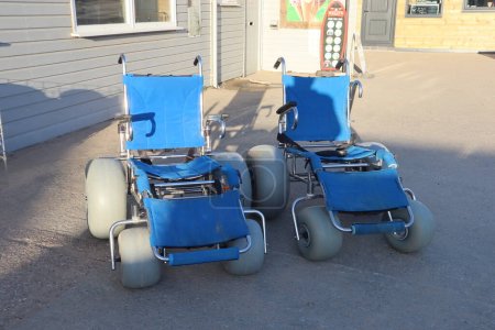 Sillas de ruedas de playa en la playa de Saunton para ancianos para ser empujados a lo largo de la arena, específicamente una silla de ruedas de playa con asas y ruedas grandes para que puedan rodar sobre la arena