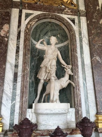 Photo for Marble statue of Roman goddess Diana in the motion with deer and arrows. Statue is located in Versailles Palace in France. Three quarters bottom view. - Royalty Free Image