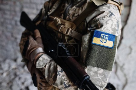 Ukrainischer Soldat in Militäruniform mit Fahne und Evron mit Dreizack - ukrainisches Emblem und Nationalsymbol