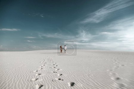 Photo for Young couple enjoying while walking in dunes. Romantic traveler walking through the Sahara desert. Adventure travel lifestyle concept. (selective focus) - Royalty Free Image