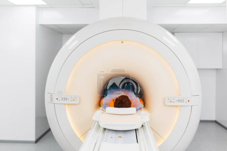 A male doctor makes an MRI of the knee joint. A young patient on an automatic table comes out of a closed-type MRI machine. Modern equipment, a coil on the patient's knee.