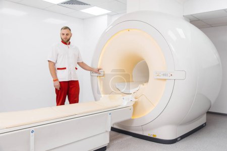 Foto de Un médico realiza una resonancia magnética o una tomografía computarizada de un paciente en una clínica moderna. Imágenes por resonancia magnética en el estudio del cuerpo humano. El médico prepara el aparato para la tomografía computarizada - Imagen libre de derechos