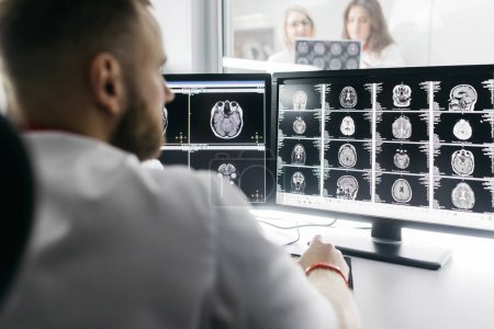 Photo for Medical hospital: neurologist use computer, analyze patient's MRI, diagnose brain. Health Clinic Lab: A professional doctor examines a functioning CT scan - Royalty Free Image