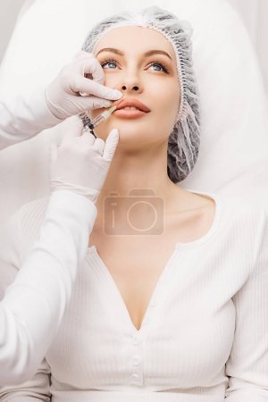 Labios femeninos sensuales recortados, aumento de labios procedimiento. Jeringa cerca de la boca de las mujeres, inyecciones para aumentar la forma de los labios