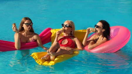 Photo for A group of beautiful young women are eating ice cream and having fun in the pool. - Royalty Free Image