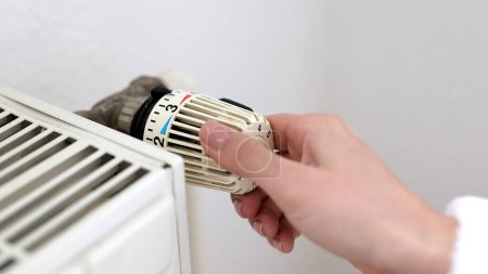 Foto de Temperatura de control manual masculino en el termostato cerca de la pared blanca. Control de calor en el sistema de calefacción central de vapor. Casa en concepto de invierno - Imagen libre de derechos