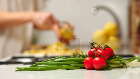 Téléchargez les photos : Close up view of woman in white shirt peeling a potato. Peel falling onto cutting board. Lady preparing potatoes to be cut and added to stock pot for dinner. - en image libre de droit