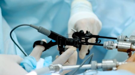 Operating room, team of surgeons performing laparoscopic intervention. Modern medicine, medical equipment in hospital. Laparoscope instruments. Doctors use endo-instruments and video cameras