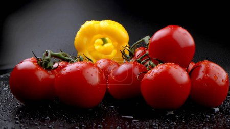 Téléchargez les photos : Tomates fraîches pour faire cuire la salade avec du poivre sur un fond sombre - en image libre de droit