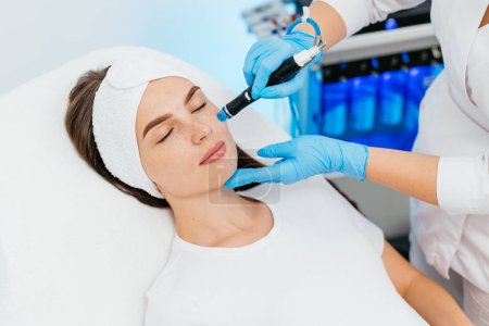 Photo for Face Skin Care. Close-up Of Woman Getting Facial Hydro Microdermabrasion Peeling Treatment At Cosmetic Beauty Spa Clinic. Hydra Vacuum Cleaner. Exfoliation, Rejuvenation And Hydratation. Cosmetology. - Royalty Free Image