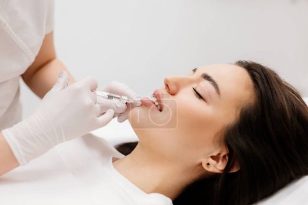Photo for The doctor cosmetologist makes Lip augmentation procedure of a beautiful woman in a beauty salon.Cosmetology skin care. High quality photo - Royalty Free Image