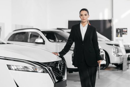 Photo for Portrait of a female car sales agent standing in front of new cars for sale in a modern car showroom - Royalty Free Image