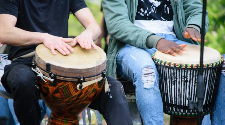 Las manos del baterista tocando el tambor de djembe étnico afuera.