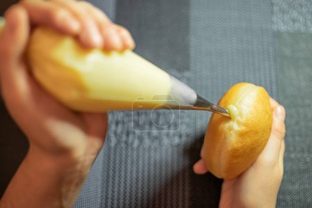Foto de Imagen de las manos llenando Krapfen tradicional con crema de vainilla. Postre de Alemania como masa de rosquillas - Imagen libre de derechos