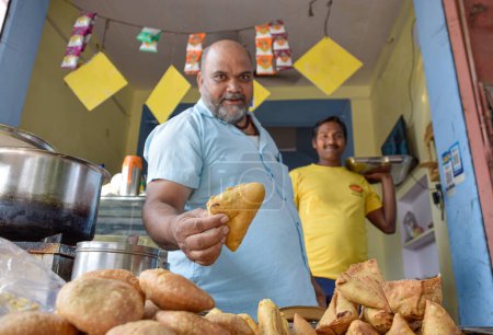 Téléchargez les photos : Vendeur offrant une collation Namkeen traditionnelle et Samosas sur la nourriture de rue et les marchés à Jaipur, Inde. - en image libre de droit
