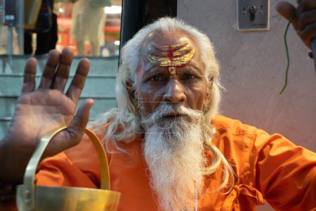 Der asketische Mönch Sadhu in Indien mit Bart, weißem Haar und geschminktem Gesicht predigt in die Kamera