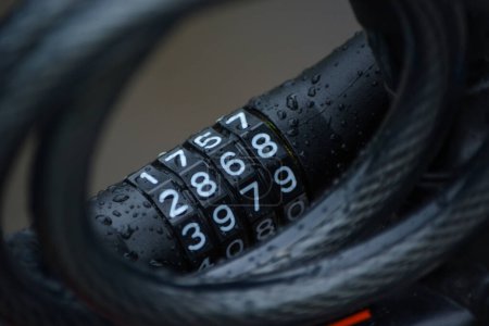 Foto de Dark bicycle lock with four white numbers in the rain closeup - Imagen libre de derechos