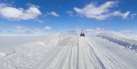 Foto de Snowmobile driving on a snow hill with beautiful sunny day - Imagen libre de derechos