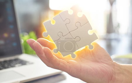 Téléchargez les photos : Close Up hand held jigsaw puzzle with sunlight affect. Business success, solutions and strategy concept - en image libre de droit
