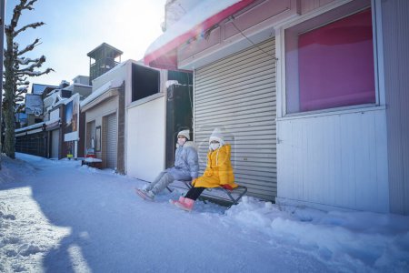 Téléchargez les photos : Deux sœurs assises et se reposant dans les rues d'Otaru, Hokkaido, voyagent en hiver - en image libre de droit