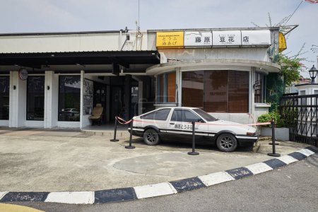Foto de IPOH, MALASIA - 28 de septiembre de 2023: Un automóvil deportivo TOYOTA AE86 blanco y negro está estacionado en la fachada del restaurante Fujiwara Tofu. - Imagen libre de derechos