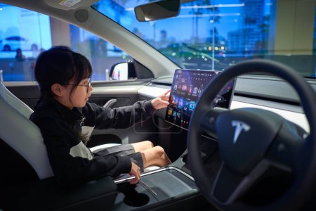 Téléchargez les photos : KUALA LUMPUR, MALAISIE - 13 NOV 2023 : La petite fille est attirée par le grand écran dans la voiture Tesla - en image libre de droit