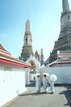 Photo for Asian family wearing Thai traditional clothes and walking on the street at Wat Arun, a famous attraction in Bangkok, Yai district, Bangkok - Royalty Free Image