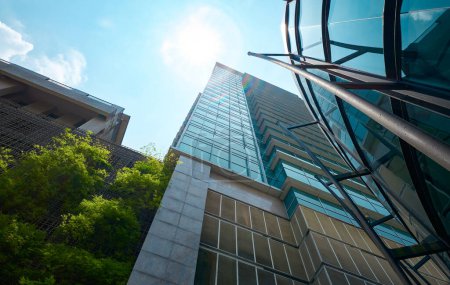 Téléchargez les photos : Vue à angle bas des bâtiments modernes en verre et vert avec un ciel lumineux - en image libre de droit