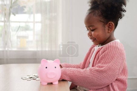 Foto de Niña poniendo moneda de efectivo en una alcancía de cerámica, hija feliz ahorrando dinero para el futuro en una alcancía - Imagen libre de derechos