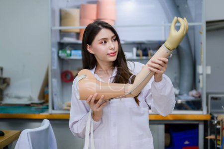 Photo for Young prosthetic technician holding prosthetic arm checking and controlling quality working in laboratory, Development specialist with high tech technology at prosthetic manufacturing, New artificial - Royalty Free Image