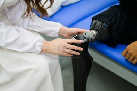 Photo for Female physician checking prosthetic leg of patient in hospital, Disables patient with treatment at health care center, New artificial limb production for disabled people - Royalty Free Image