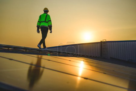 Téléchargez les photos : Ingénieur travaillant à la centrale solaire avec coucher de soleil dans la soirée, Énergie solaire avec ciel chaud, Énergie propre, Énergie alternative - en image libre de droit