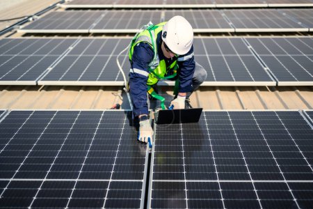 Téléchargez les photos : Ingénieurs professionnels avec casque de sécurité vérifiant le système solaire à la ferme d'énergie solaire, Techniciens avec cellule solaire sur le toit de l'usine d'énergie, Concept de ressources durables - en image libre de droit