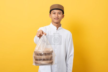 Photo for Young handsome asian muslim man giving alms or charity standing over orange background. happy ramadan and eid al-fitr. - Royalty Free Image