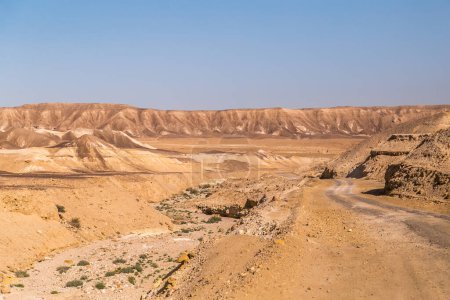 Photo for Rocky Mountains in Israel next to gravel dusty and unpaved road through the arid dry Judean Desert in the  Midbar Yehuda. Small Crater to Highway #90 and Golan Trail. Landscape of the Negev Desert. - Royalty Free Image