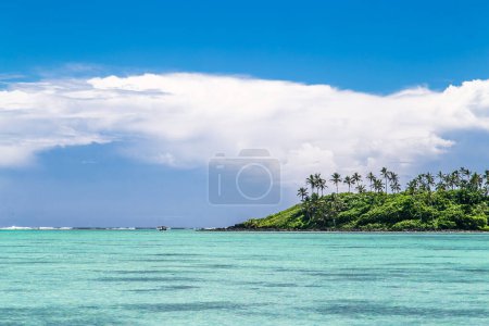 Tropische Bucht, paradiesische Destination auf den Cook Islands. Tropische Lagune in Rarotonga, Küste mit Korallen. Blaues Meer mit kristallklarem türkisfarbenem Wasser und Palmen an sonnigen Tagen. Azurblauer Himmel mit Wolken. Leicht bewölkt.
