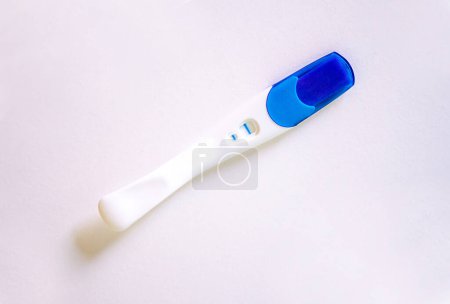Positive pregnancy test with two stripes on white table. High quality photo