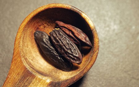 Tonka Beans in a wooden Spoon on a dark background.