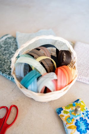 Photo for Sewing still life with a basket full of coloured zips, needle cushion and scissors to talk about sewing and creating - Royalty Free Image