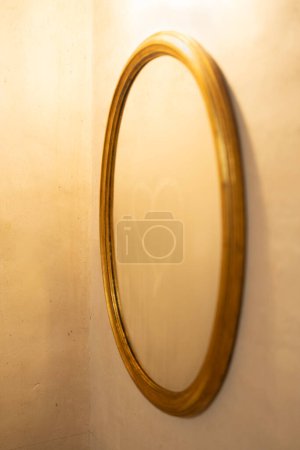 Espejo con marco dorado con vidrio empañado, dibujado un corazón, fotografía vertical con fondo de textura de cemento de color crema.