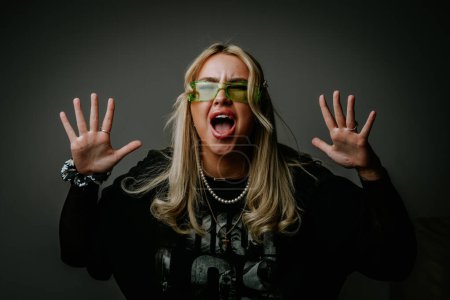 Photo for Happy blonde girl shouts yes, celebrates victory, achieves goal. Human emotions, facial expression concept. Studio photo, dark gray background. - Royalty Free Image