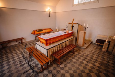 An open wooden coffin is placed in the chapel