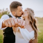 Happy diverse bride and groom showing rings to camera at outdoor wedding, selective focus