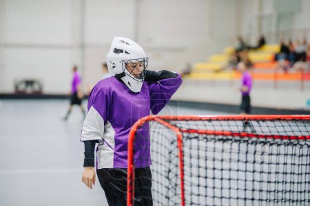 Photo for Close-up of woman floorball goalkeeper in helmet concetrating on game in gym. - Royalty Free Image